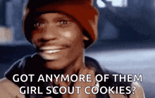 a man wearing a red beanie is smiling and asking if he has anymore girl scout cookies .