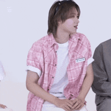 a man wearing a pink plaid shirt has a name tag on his chest that says ' a ' on it