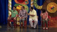 a group of people are sitting in chairs in front of a colorful background