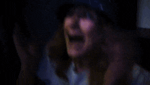 a woman wearing a blue hat with spikes on it is making a funny face