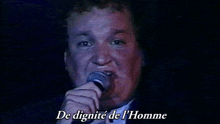 a man singing into a microphone with the words " de dignite de l' homme " below him