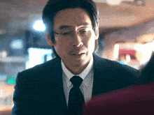 a man wearing glasses and a suit is looking at a woman