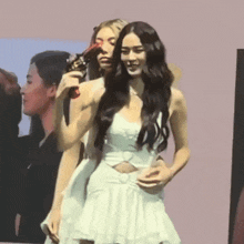 a woman in a white dress is standing next to another woman in a black shirt .