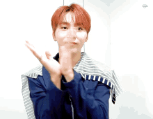 a young man with red hair is clapping his hands in front of a white wall