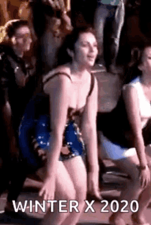 a woman in a bathing suit is dancing in front of a crowd at a party .