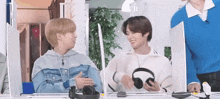 two boys are sitting at a table with headphones on .