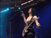 a man without a shirt is singing into a microphone while playing a guitar