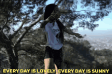 a girl stands in front of a tree with the words every day is lovely