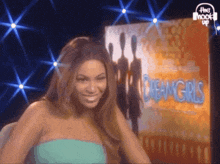 a woman is smiling in front of a poster for dream girls