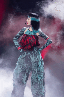 a woman with blue hair is standing in front of a microphone in a dark room