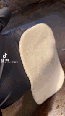 a person wearing black gloves is holding a piece of dough with a tiktok watermark