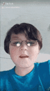 a young boy wearing glasses and a blue shirt .