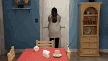 a woman in a white coat is standing in front of a door in a kitchen