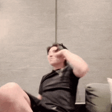 a man is sitting on a couch flexing his muscles and giving a thumbs up .