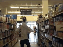 a woman is walking down a grocery store aisle with a sign above her that says ' the depot to dream on '