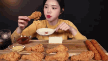 a woman in a yellow sweater is eating fried chicken with a spoon