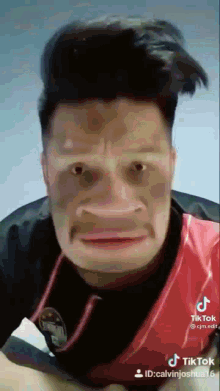 a man in a red shirt is making a funny face with his mouth open .