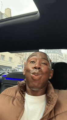 a man in a brown jacket is making a funny face