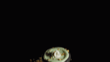 a bowl of food is being poured on a table with a black background