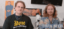 two men are standing next to each other in front of a microphone wearing headphones and a shirt that says bone