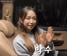 a woman is sitting in the back seat of a car and clapping her hands .