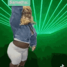 a woman in a denim jacket is dancing in front of a green background .