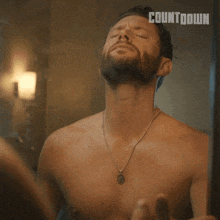 a shirtless man is looking at himself in a mirror with the word countdown behind him