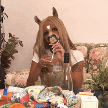 a woman wearing a horse mask drinking from a glass