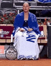 a woman is sitting on a bench with a tennis racquet and a towel that says ' roma ' on it