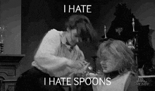 a black and white photo of two women fighting over a spoon and the words `` i hate spoons '' .