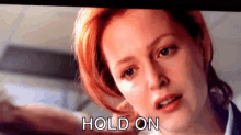 a close up of a woman 's face with the words `` hold on '' written on the bottom .