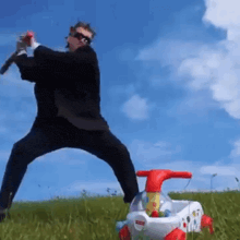 a man in a suit is playing with a fisher price toy car