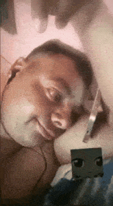 a man wearing headphones is laying on a bed with a toy in his hand .