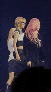 a group of women are dancing on a stage and one of them has pink hair