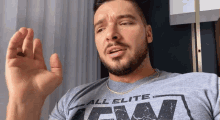 a man with a beard wearing a grey shirt that says all elite