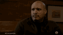 a bald man covering his face with his hand in a scene from chicago fire on nbc