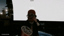 a man in a red hat and glasses is holding a bowl of nuggets in front of a screen that says manakeitin