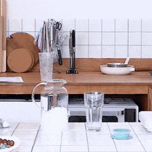 a kitchen counter has a pitcher of water and a glass of water