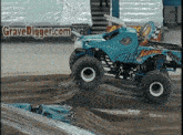 a monster truck is on a dirt track with a gravedigger.com sign in the background