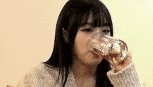 a young woman is drinking a glass of liquid from a glass .