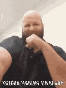 a bald man with a beard is making a funny face with his fist in his mouth .