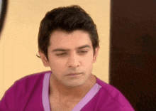 a man in a purple shirt is looking at something