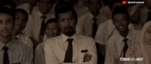 a man in a white shirt and tie stands in front of a group of people