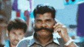 a man with a big mustache talking on a cell phone