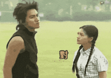 a man and a woman are standing next to each other in a field with chinese characters on the ground