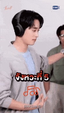 a young man wearing headphones and a blue shirt is standing in front of a wall .