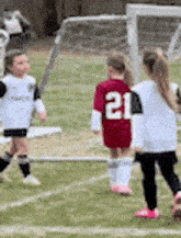 a group of young children are playing soccer on a field . one of the children is wearing a number 21 jersey .