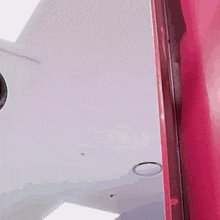 a close up of a mirror in a room with a pink wall .