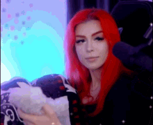 a woman with red hair is sitting in a chair holding a white cat .