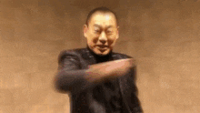 a man in a black leather jacket is making a funny face while dancing .